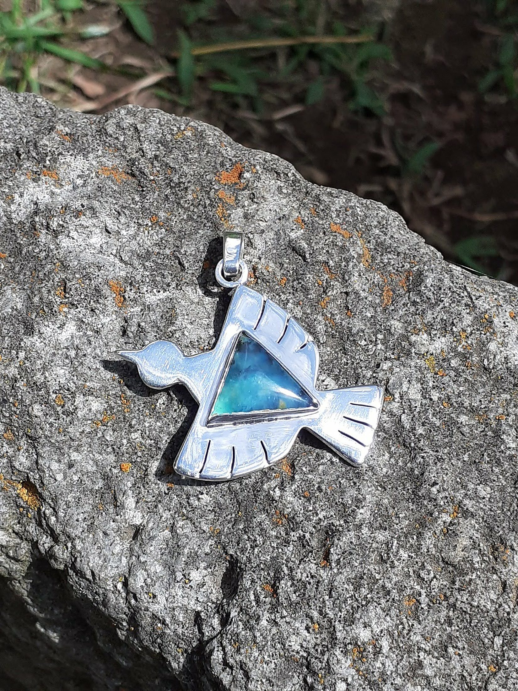 Dije cóndor de plata sobre roca andina